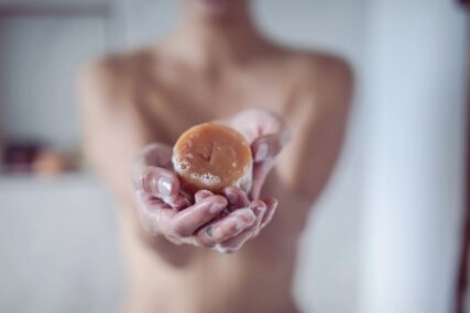 Naked women holdinghemp collective orange, grapefruit and lemon shampoo bar
