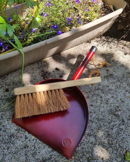 ECOMAX Metal Dustpan Red and Dust Brush outside on concrete floor near garden