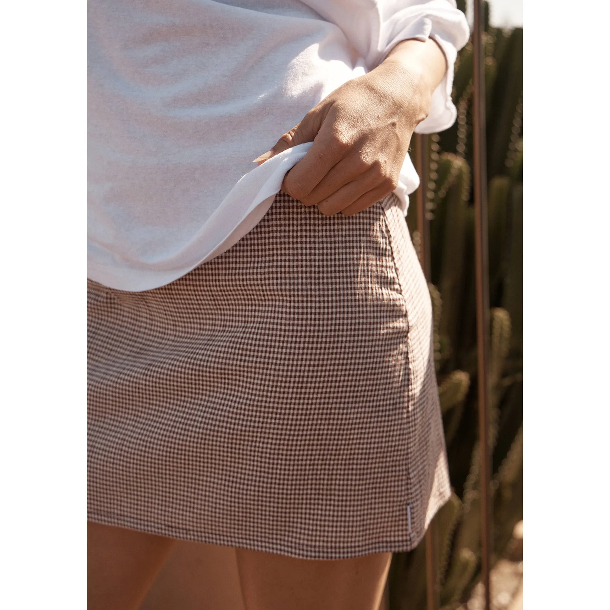 Close-up of the Mahogany Check fabric on the Afends Mariah Mini Skirt, worn with a white tee
